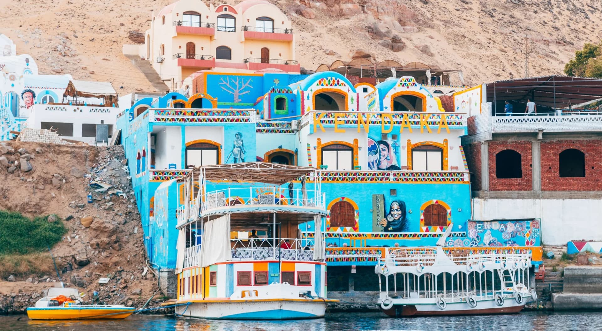 Casas de colores de una aldea nubia junto al Nilo, con barcos amarrados